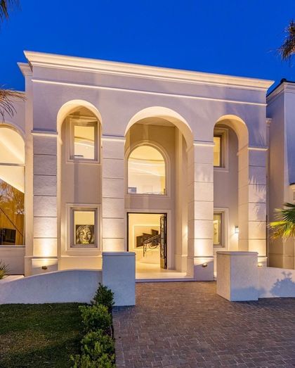 Fachada contemporánea blanca iluminada con arcos altos y ventanales — proyecto TRV 153, por Estudio Arq Daniel Tarrio