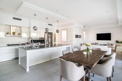 Comedor moderno con mesa madera y cocina isla blanca integrada — proyecto TRV 153, por Estudio Arq Daniel Tarrio