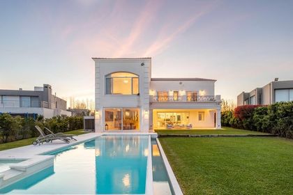 Casa moderna con pileta, fachada blanca y gran ventanal iluminado — proyecto TRV 153, por Estudio Arq Daniel Tarrio