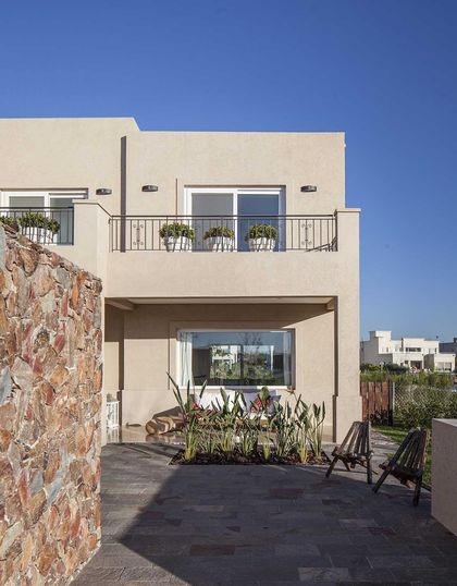 Patio moderno con deck y fachada blanca minimalista bajo cielo azul — proyecto TRV 137, por Estudio Arq Daniel Tarrio