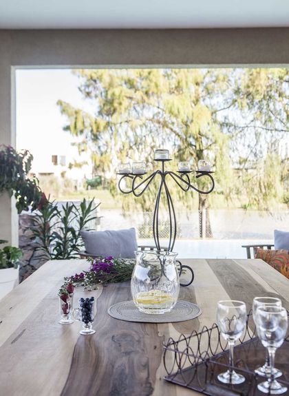 Comedor moderno con mesa de madera, candelabro hierro y vista jardin — proyecto TRV 137, por Estudio Arq Daniel Tarrio