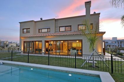 Casa moderna con pileta iluminada al atardecer, fachada vidriada — proyecto TRV 195, por Estudio Arq Daniel Tarrio