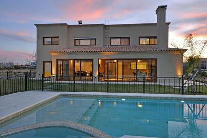 Casa moderna con pileta iluminada al atardecer, fachada vidriada — proyecto TRV 195, por Estudio Arq Daniel Tarrio