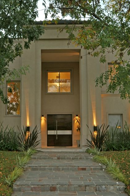Fachada contemporánea con entrada iluminada y vegetación envolvente — proyecto SP, por Estudio Arq Daniel Tarrio