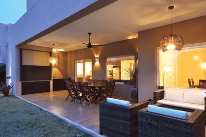 Patio con deck, muebles de ratan y iluminacion cálida al atardecer — proyecto LP 149, por Estudio Arq Daniel Tarrio