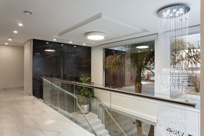 Pasillo moderno con escalera de vidrio y doble altura luminoso — proyecto TRV 490, por Estudio Arq Daniel Tarrio