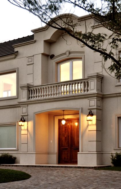 Fachada clásica con puerta de madera, balconada y molduras decorativas — proyecto Ayres del Pilar, por Marconi Silva Arquitectos, en Pilar