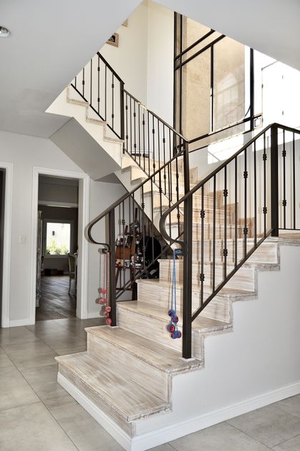 Escalera moderna con barandas de hierro negro y peldaños en madera clara — proyecto Buenos Aires Village, por Marconi Silva Arquitectos, en Bella Vista