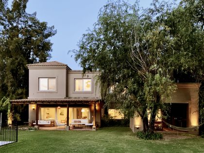 Casa moderna con jardin, pergola iluminada al atardecer y arboles — proyecto El Encuentro , por Marconi Silva Arquitectos, en Benavidez