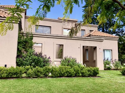 Casa contemporánea beige con fachada abierta y jardín verde frontal — proyecto El Encuentro , por Marconi Silva Arquitectos, en Benavidez