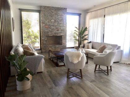 Living moderno con sillones, hogar de ladrillo y grandes ventanales — proyecto Golf Club Nordelta, por Marconi Silva Arquitectos, en Nordelta