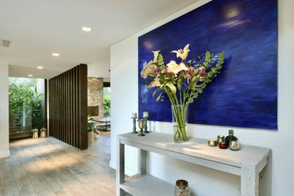 Pasillo moderno con pared azul, consola blanca y flores frescas — proyecto Golf Club Nordelta, por Marconi Silva Arquitectos, en Nordelta
