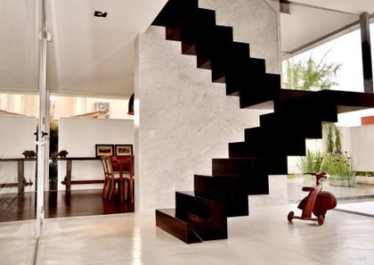 Escalera flotante negra en espacio minimalista blanco con doble altura — proyecto Haras Santa María, por Marconi Silva Arquitectos, en Escobar