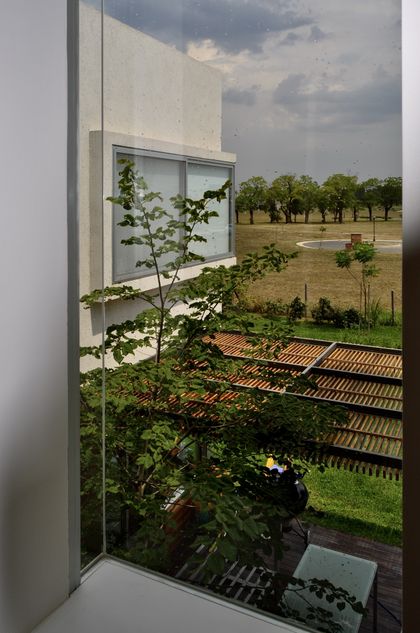 Terraza minimalista con pergola de madera y campo al fondo — proyecto Haras Santa María, por Marconi Silva Arquitectos, en Escobar