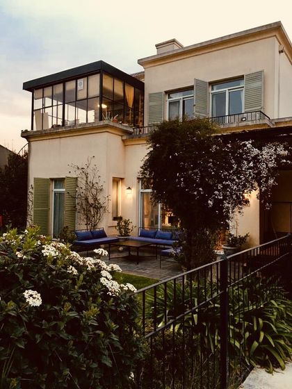 Patio contemporáneo con pérgola, jardín vertical y luces cálidas al atardecer — proyecto Lagos del Norte, por Marconi Silva Arquitectos, en Don Torcuato