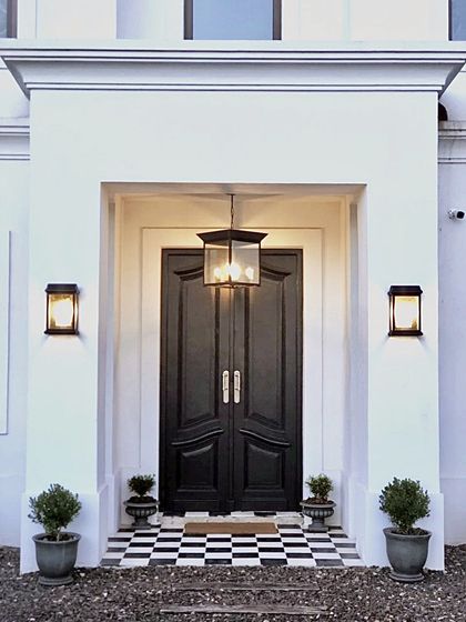 Fachada clasica en blanco y negro con puerta doble y luminarias — proyecto San Matías, por Marconi Silva Arquitectos, en Belén de Escobar