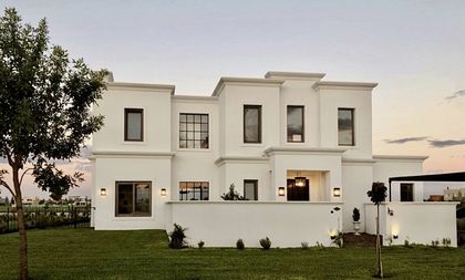 Casa moderna blanca con ventanales grandes y árbol adelante al atardecer — proyecto San Matías, por Marconi Silva Arquitectos, en Belén de Escobar