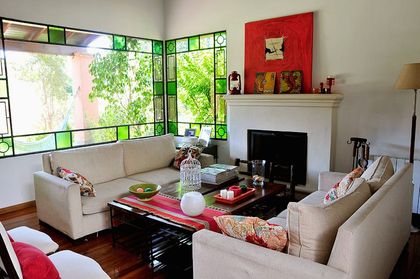 Living moderno con ventanales grandes y sillones claros de cuero — proyecto Valle Claro, por Marconi Silva Arquitectos, en Benavidez