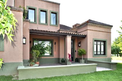 Fachada beige de casa moderna con ventanas y entrada de madera — proyecto Valle Claro, por Marconi Silva Arquitectos, en Benavidez