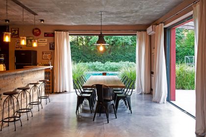 Comedor industrial con mesa de madera y vista al jardín — proyecto Casa JP, por Ricardo Pereyra Iraola 
