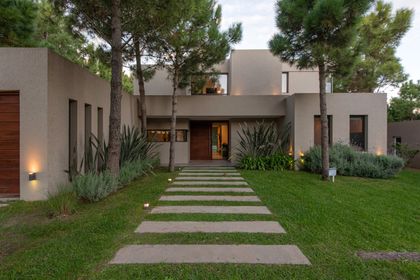 Fachada moderna con hormigón visto y vegetación exuberante — proyecto Costa Esmeralda 1, por Arquitecto Caceres, en Costa Esmeralda