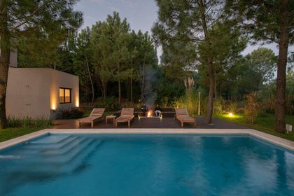 Piscina moderna con fogón y deck en entorno boscoso — proyecto Costa Esmeralda 1, por Arquitecto Caceres, en Costa Esmeralda