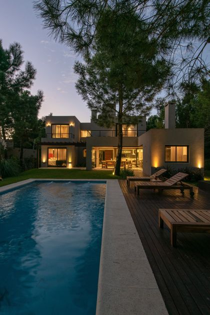 Casa moderna con piscina y deck, iluminación cálida nocturna — proyecto Costa Esmeralda 1, por Arquitecto Caceres, en Costa Esmeralda
