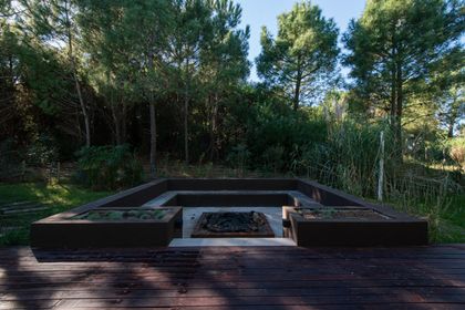 Parque moderno con parrilla empotrada y deck de madera oscura — proyecto Costa Esmeralda 1, por Arquitecto Caceres, en Costa Esmeralda
