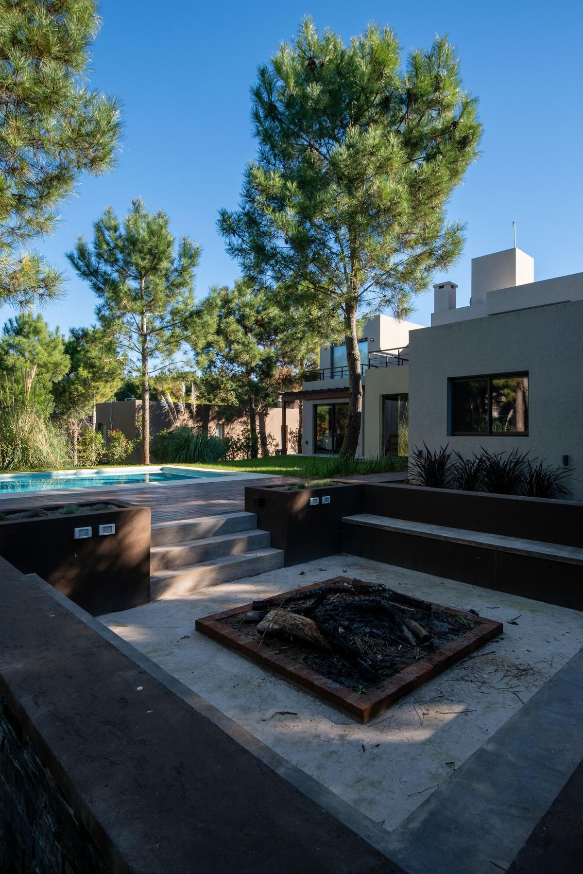 Área externa moderna com piscina, lareira e arquitetura brutalista — projeto Costa Esmeralda 1, por Arquitecto Caceres, em Costa Esmeralda