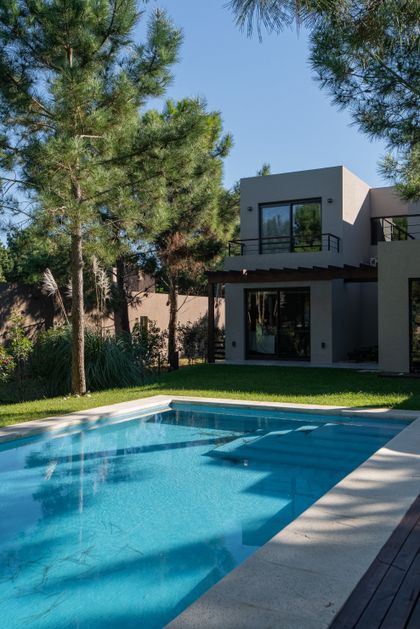 Casa moderna con piscina y árboles en entorno suburbano — proyecto Costa Esmeralda 1, por Arquitecto Caceres, en Costa Esmeralda