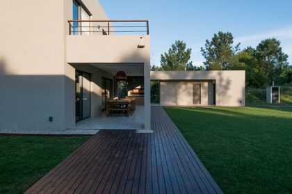 fachada moderna con deck de madera y césped — proyecto Costa Esmeralda 2, por Arquitecto Caceres, en Costa Esmeralda