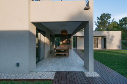Patio moderno cubierto con mesa de madera y parrilla — proyecto Costa Esmeralda 2, por Arquitecto Caceres, en Costa Esmeralda