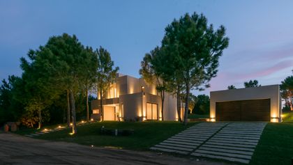 Fachada moderna con volúmenes geométricos e iluminación cálida — proyecto Costa Esmeralda 2, por Arquitecto Caceres, en Costa Esmeralda