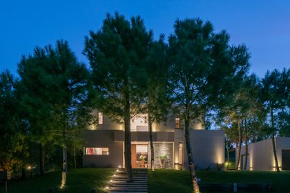 fachada moderna con iluminación ambiental y vegetación prominente — proyecto Costa Esmeralda 2, por Arquitecto Caceres, en Costa Esmeralda