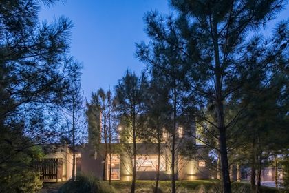 fachada moderna de casa en bosque iluminada de noche — proyecto Costa Esmeralda 2, por Arquitecto Caceres, en Costa Esmeralda