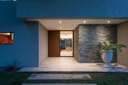 Entrada moderna de casa con muro de piedra y detalles en madera — proyecto Costa Esmeralda 2, por Arquitecto Caceres, en Costa Esmeralda