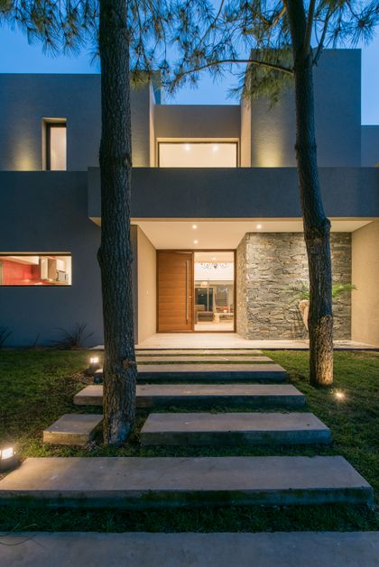 Fachada moderna con entrada de madera y senderos de hormigón — proyecto Costa Esmeralda 2, por Arquitecto Caceres, en Costa Esmeralda