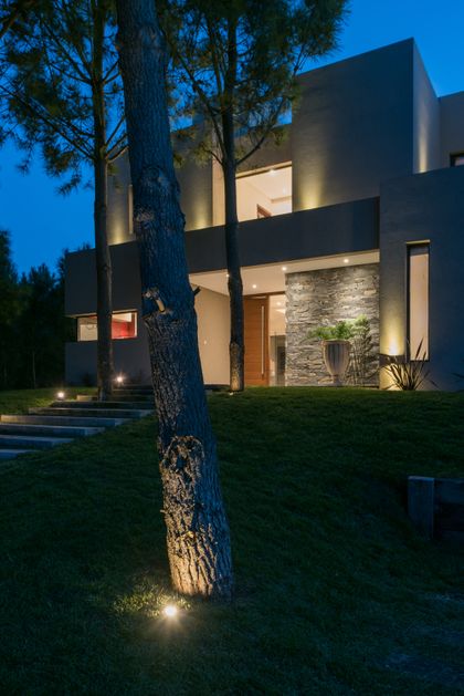 fachada moderna con iluminación indirecta y árboles — proyecto Costa Esmeralda 2, por Arquitecto Caceres, en Costa Esmeralda