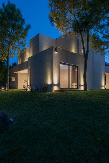 Fachada moderna con iluminación indirecta cálida y volúmenes geométricos — proyecto Costa Esmeralda 2, por Arquitecto Caceres, en Costa Esmeralda
