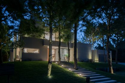 fachada moderna minimalista de noche, rodeada de vegetación — proyecto Costa Esmeralda 2, por Arquitecto Caceres, en Costa Esmeralda