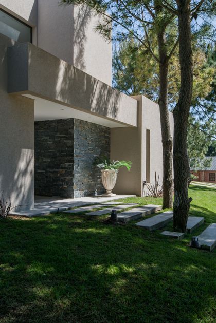 Fachada moderna de hormigón con piedra y vegetación integrada — proyecto Costa Esmeralda 2, por Arquitecto Caceres, en Costa Esmeralda