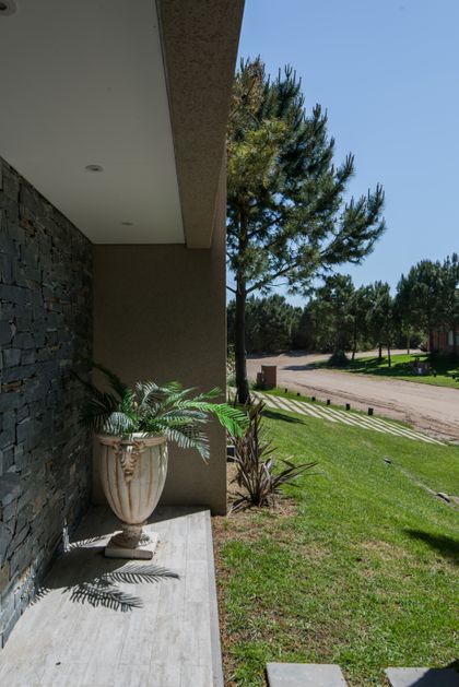 Fachada moderna con detalles rústicos y gran macetero — proyecto Costa Esmeralda 2, por Arquitecto Caceres, en Costa Esmeralda