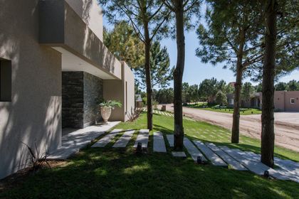 Fachada moderna con camino de piedra y césped — proyecto Costa Esmeralda 2, por Arquitecto Caceres, en Costa Esmeralda