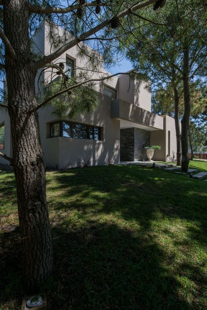 Fachada moderna en campo con piedra y hormigón, rodeada de árboles — proyecto Costa Esmeralda 2, por Arquitecto Caceres, en Costa Esmeralda