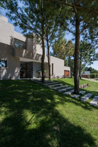 fachada moderna con escalones de piedra y pinos — proyecto Costa Esmeralda 2, por Arquitecto Caceres, en Costa Esmeralda
