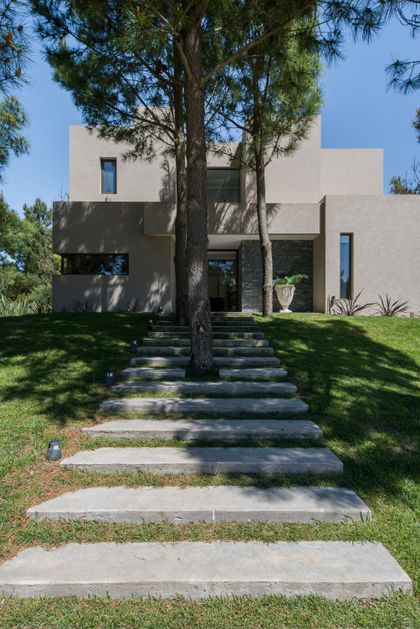 fachada moderna con escalones de hormigón y árboles integrados — proyecto Costa Esmeralda 2, por Arquitecto Caceres, en Costa Esmeralda