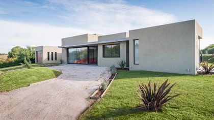 Fachada moderna con entrada de grava y césped — proyecto Costa Esmeralda 3, por Arquitecto Caceres, en Costa Esmeralda