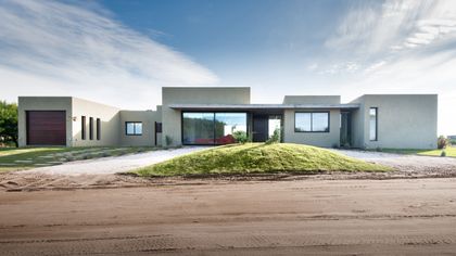Casa moderna de hormigón con grandes ventanales y césped elevado — proyecto Costa Esmeralda 3, por Arquitecto Caceres, en Costa Esmeralda
