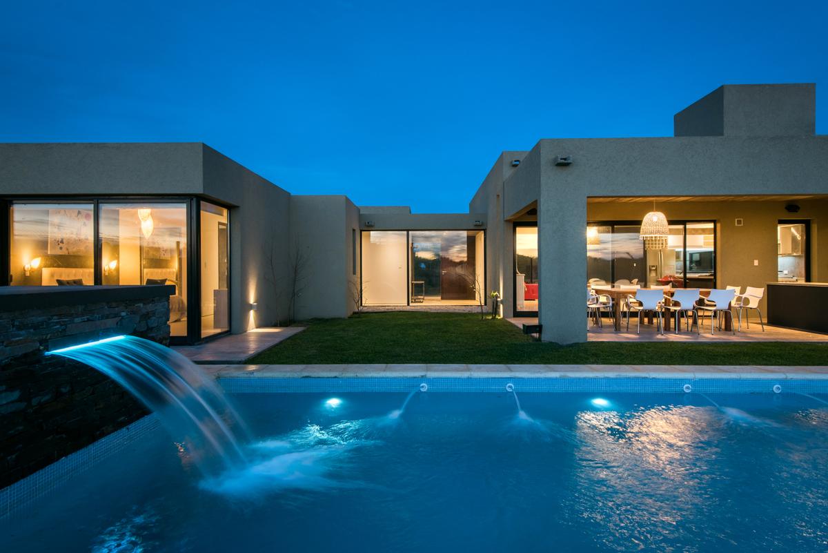 Residência moderna com piscina e pátio coberto ao entardecer — projeto Costa Esmeralda 3, por Arquitecto Caceres, em Costa Esmeralda