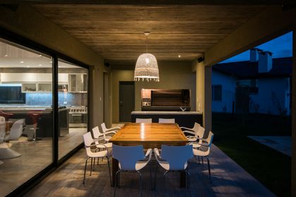 Comedor exterior moderno con techo de madera y gran lámpara colgante — proyecto Costa Esmeralda 3, por Arquitecto Caceres, en Costa Esmeralda